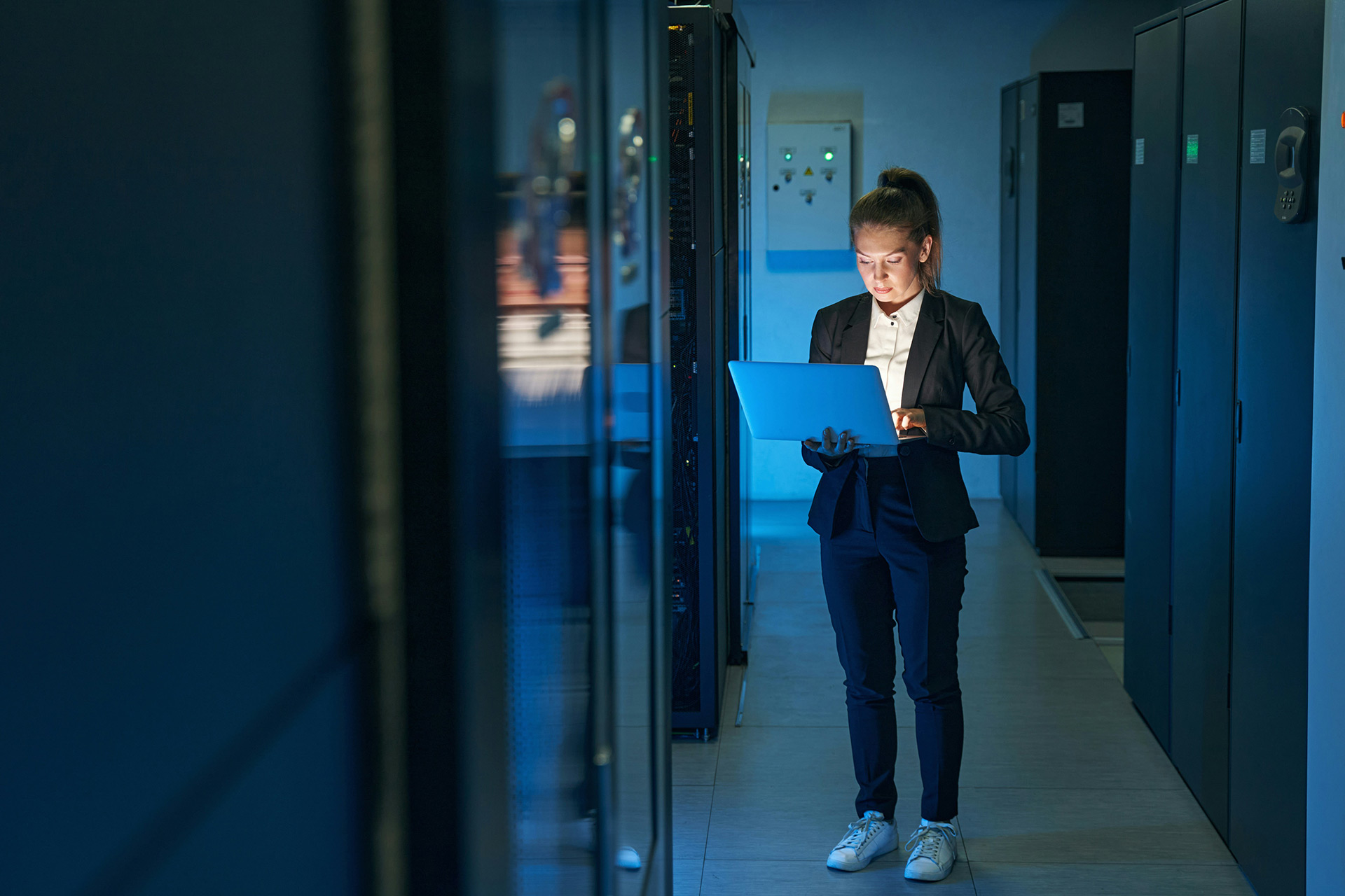 Kvinna står vid dator och analyserar värmeutvecklingen i serverhallen